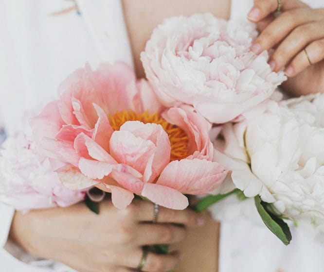 Hands delicately cradle a stunning bouquet of pink and white peonies, exuding a sense of elegance that reflects artful branding.