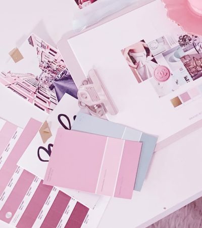 A workspace with rebrand-ready materials: color swatches, pink paint samples, a sketch pad, and a keyboard, showcasing design and planning essentials.