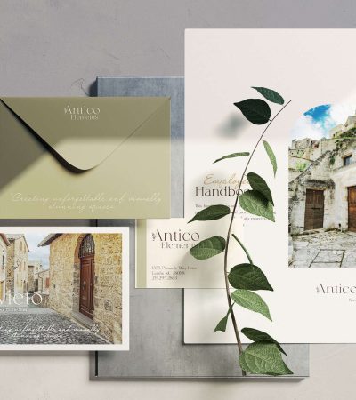 A flat lay display of stationery items, including envelopes, postcards, and a brochure featuring rustic stone buildings and a green leafy branch—perfect for inspiring confidence and overcoming self doubt in your daily correspondence.
